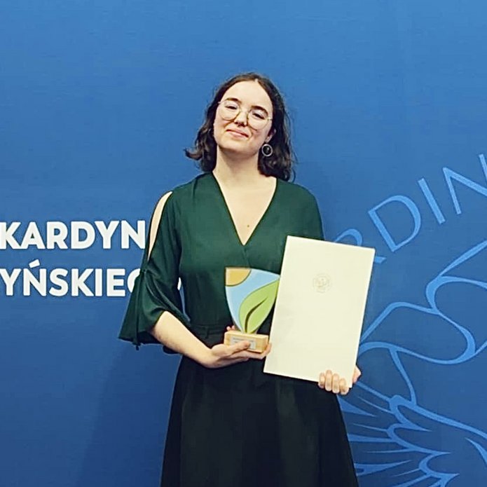 Osoba pozująca do zdjęcia z nagrodą w ręku